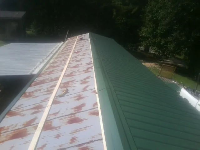 Old rusted panels beside newly installed green metal roofing — Wind Damage Roof Repair by Roofing Brothers in Tremont